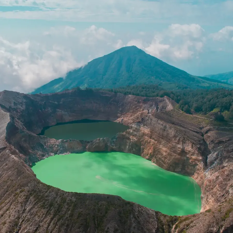 A green crater lake seen from the rim of Kelimutu, a volcanic cone behind
